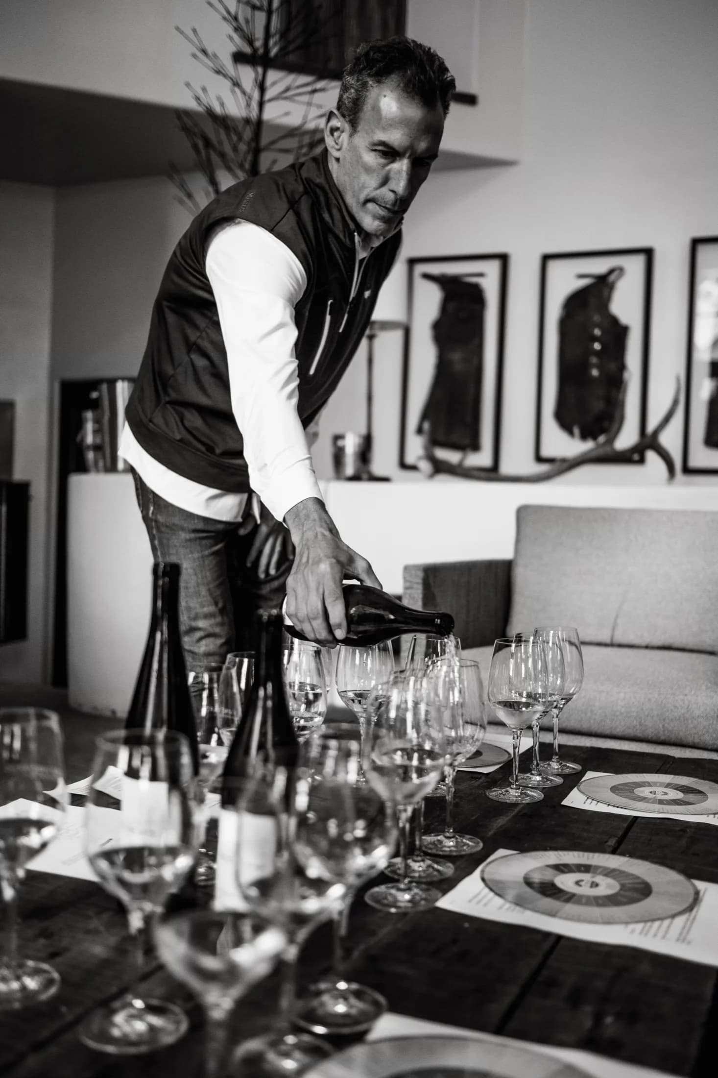 A sommelier pours wine at an intimate, art-lined tasting table.